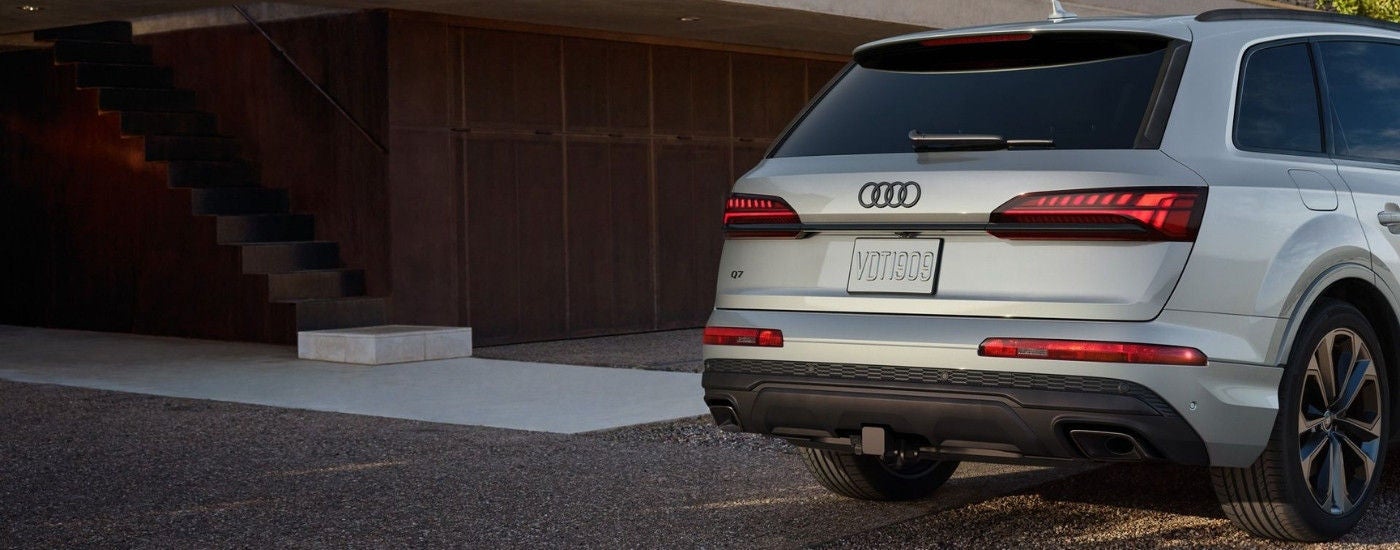 A silver 2025 Audi Q7 parked in a driveway near stairs.